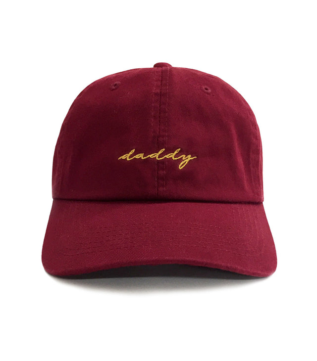 Daddy Hat – Maroon 6-panel cotton dad hat with gold embroidered “Daddy” script, adjustable strap, lightweight and comfortable gift for dads.